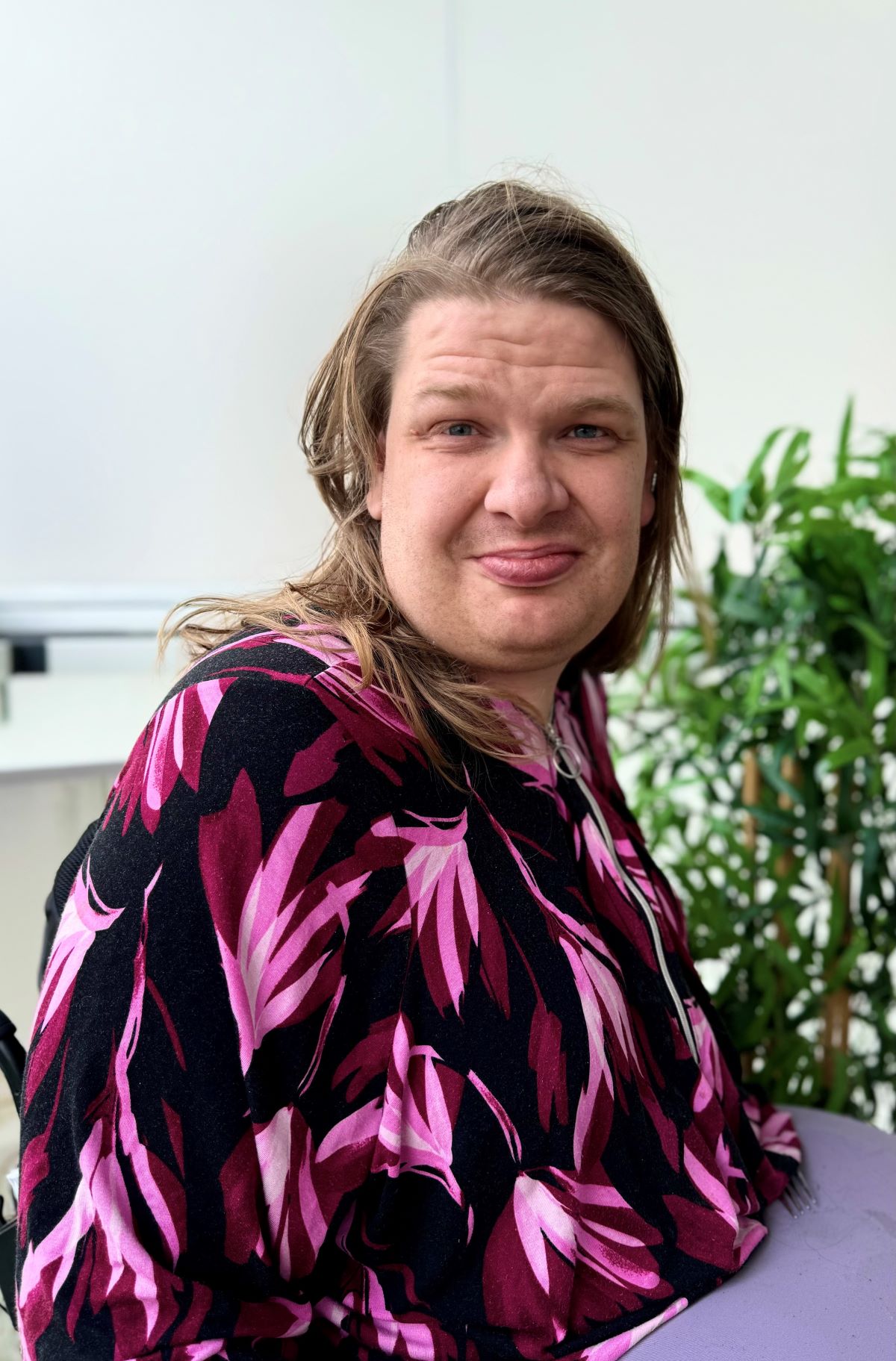 Henkilö katsoo hymyillen kameraan.